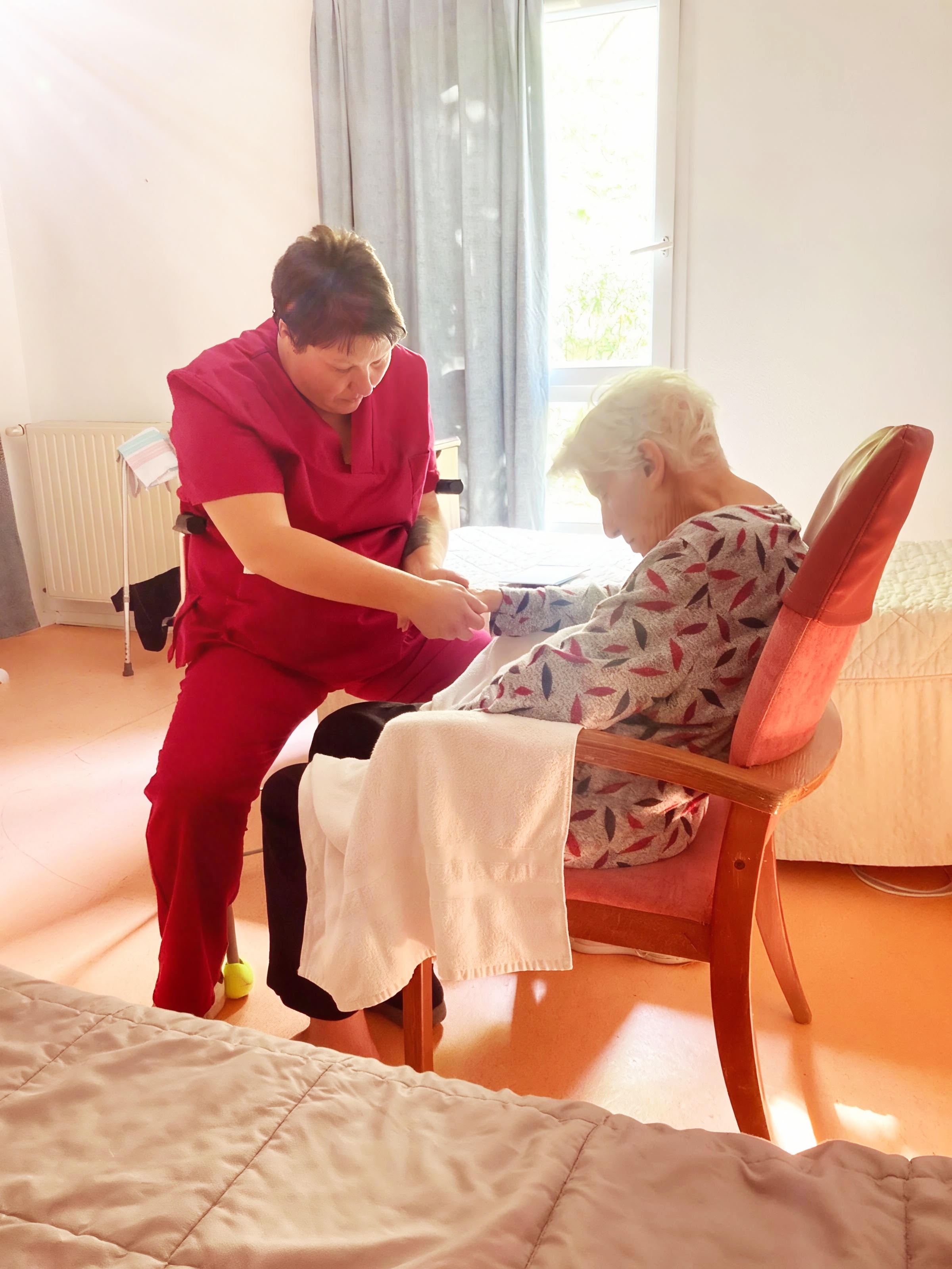 Adeline réalise un toucher-contact auprès d'une personne âgée assise.